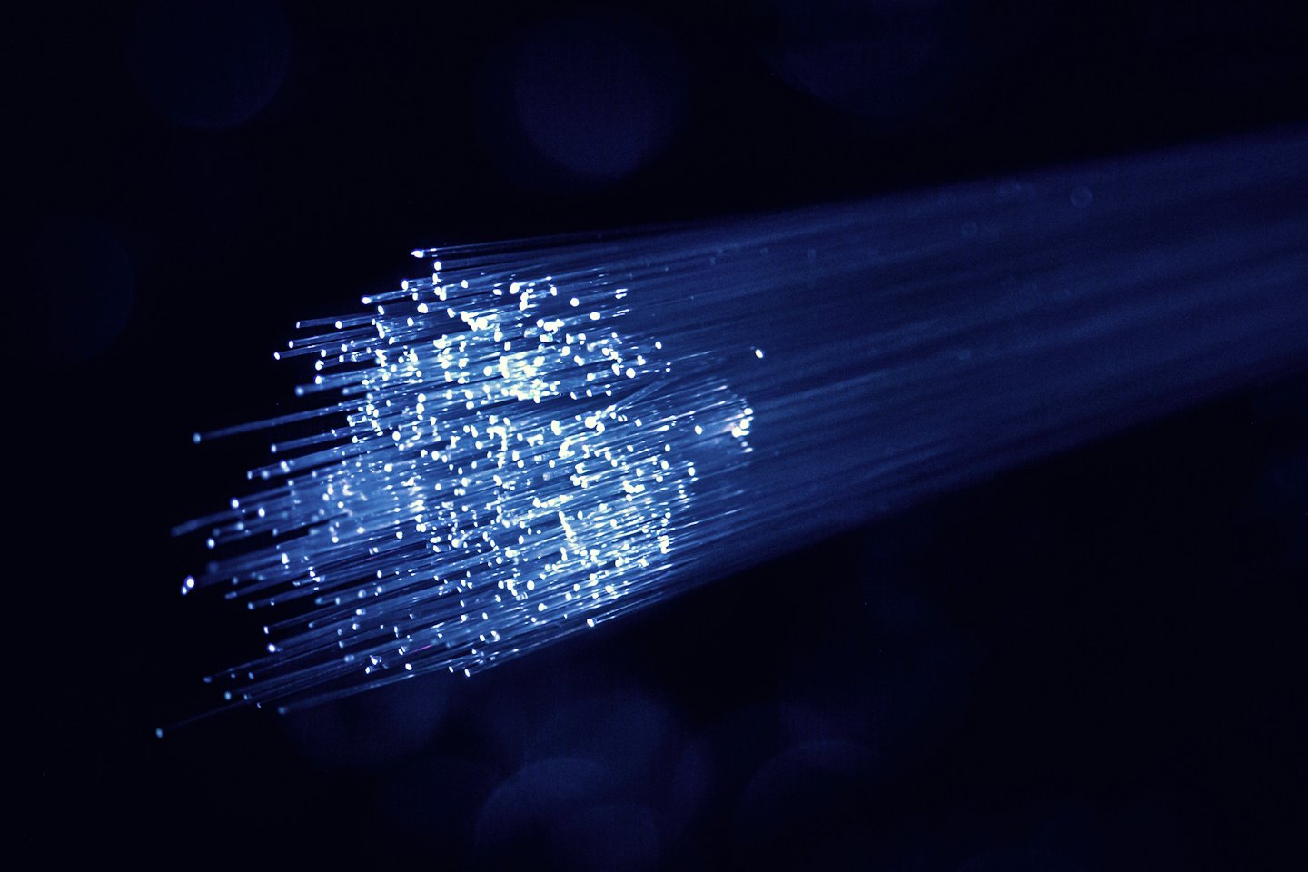 Cables de fibra óptica azules brillantes transmitiendo datos.