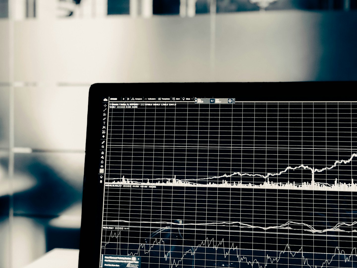 Pantalla de portátil con gráficos y diagramas financieros sobre fondo negro.